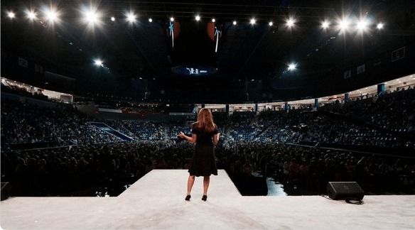 Summit delegate speaking on the main stage to a packed arena